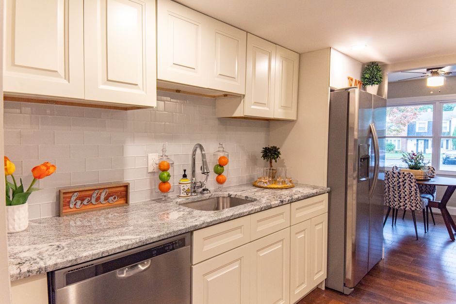A stylish modern kitchen featuring white cabinets, granite countertops, and a stainless steel refrigerator. Bright and inviting.